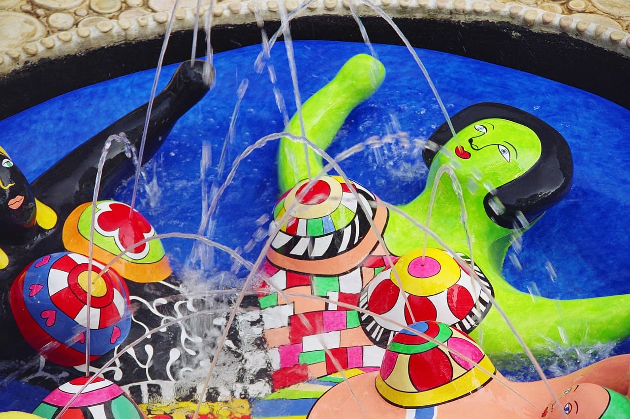 Sculpture colorée de Niki de Saint Phalle avec figures féminines et jets d’eau.