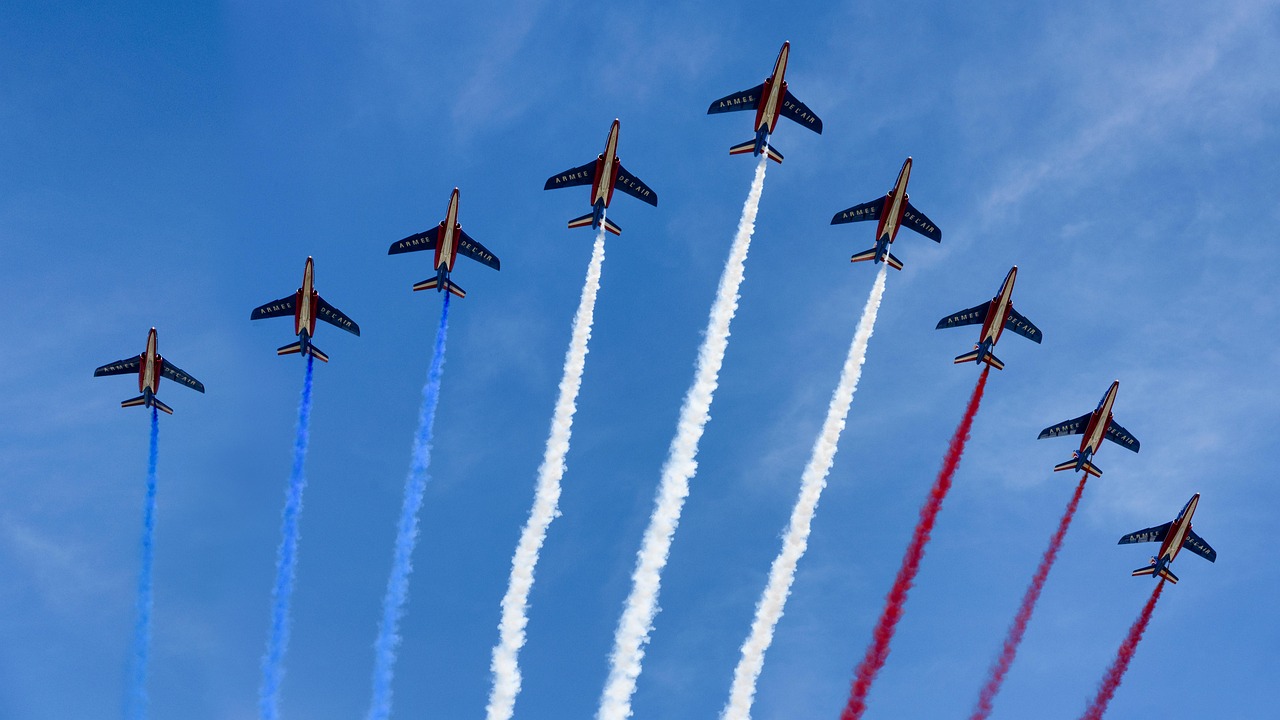 Neuf avions traçant des fumées bleu, blanc, rouge dans le ciel.